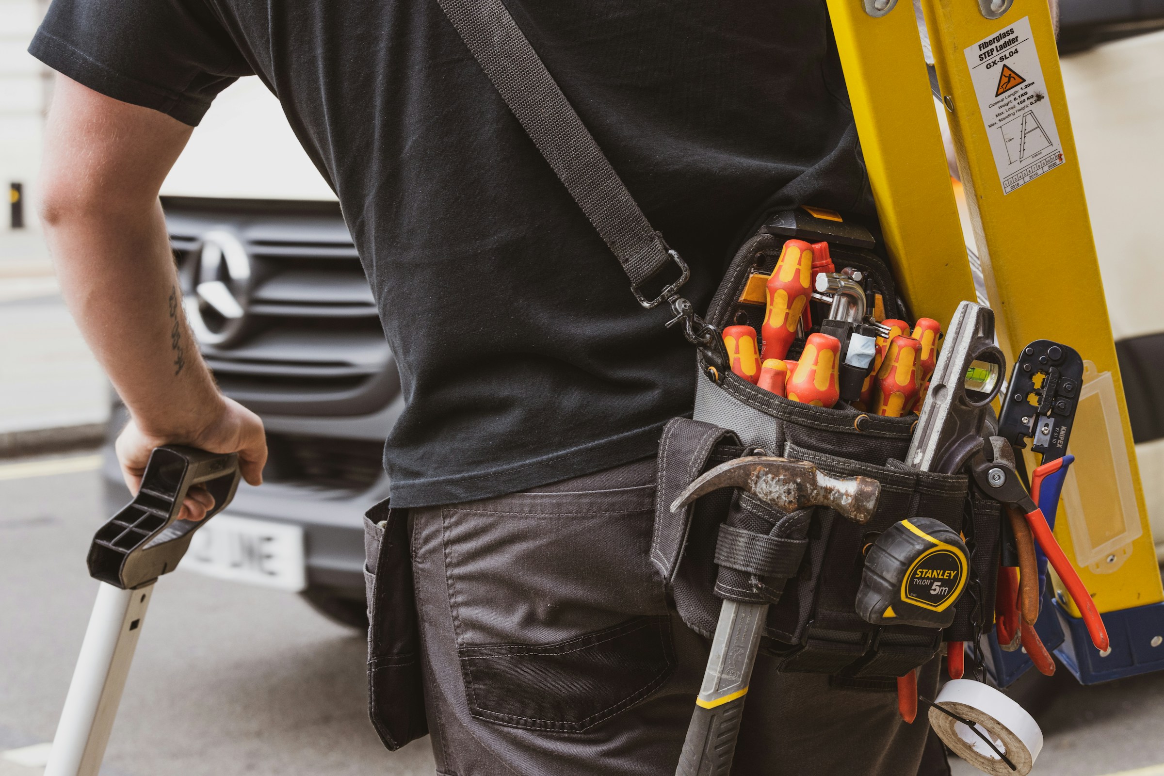 Technician arriving with a tool belt and ladder for a scheduled tune-up